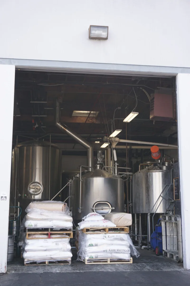 Sacks of malt stacked beside the brewhouse tanks