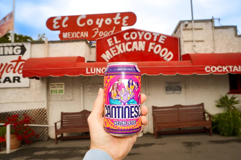 A hand raising a Cantinesca can outside El Coyote Mexican Food