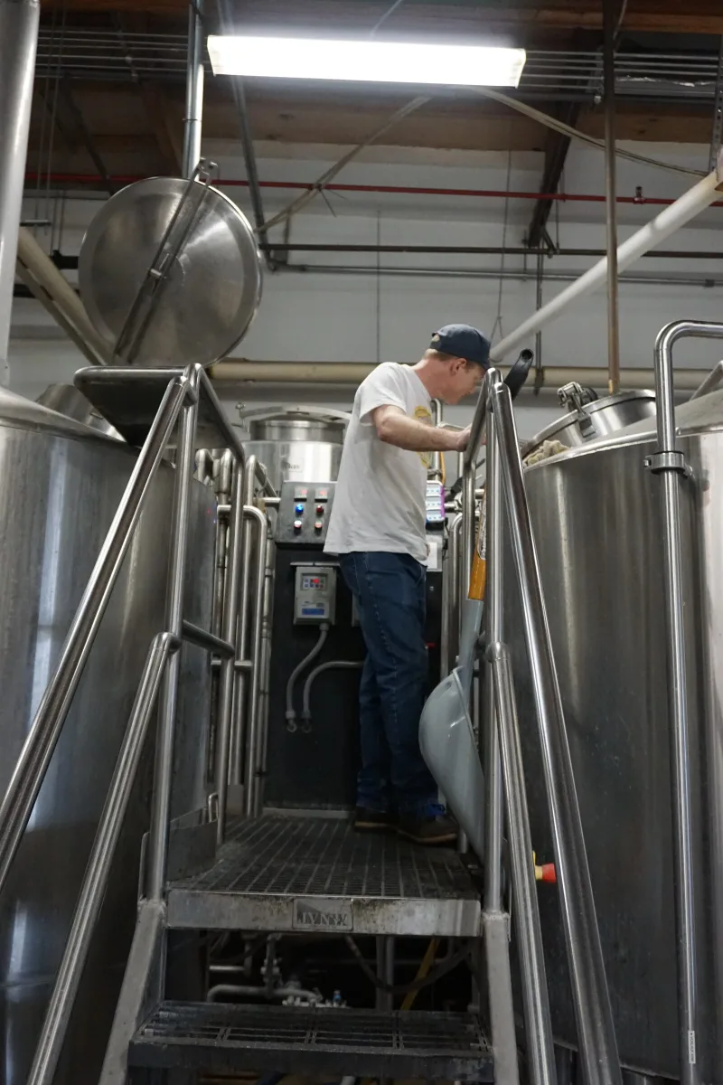 Brewer working the kettle on the brewhouse stairs
