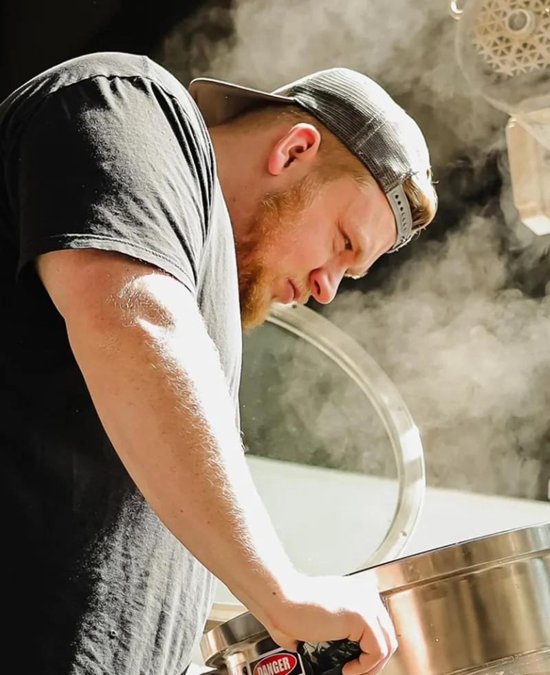 A brewer working over an open kettle